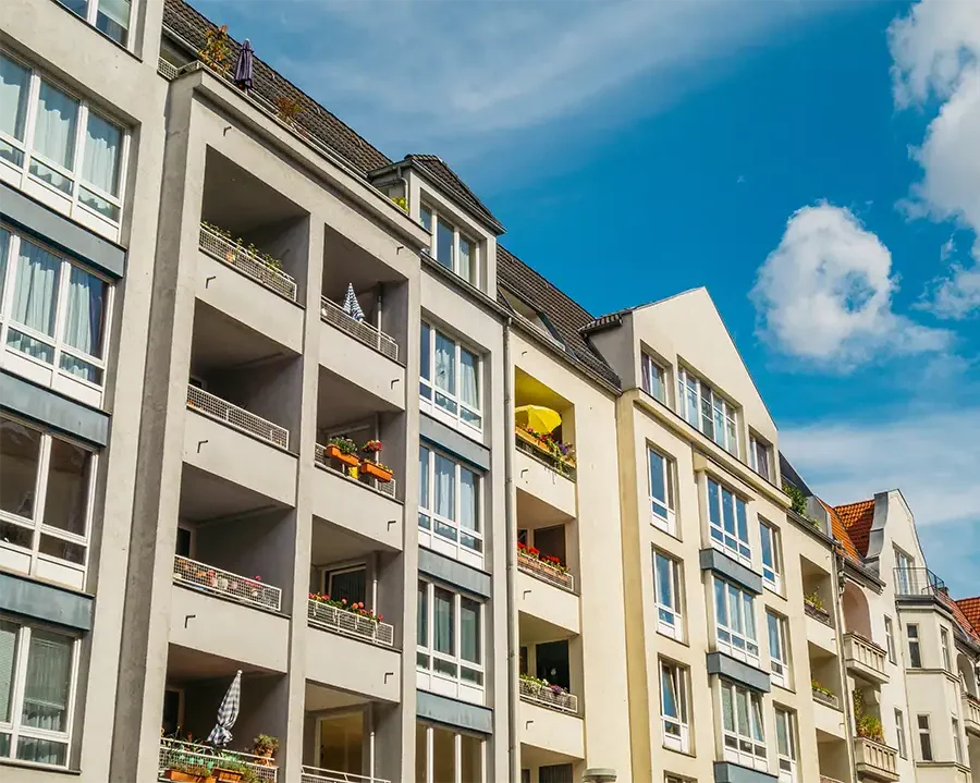 Großer moderner Wohnblock mit vielen Eigentumswohnungen unter blauem Himmel.
